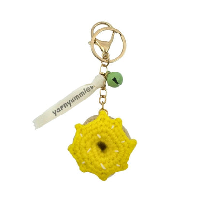 Yellow donut-shaped crocheted keychain with a tag labeled 'yarnymummies' on a white background