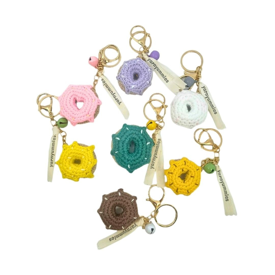 Colorful donut-shaped crochet keychains with unique designs on a white background