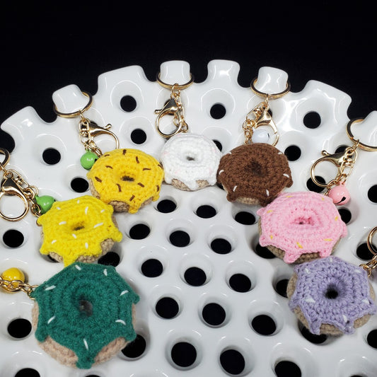 Colorful crocheted donut keychains on a white and black patterned surface