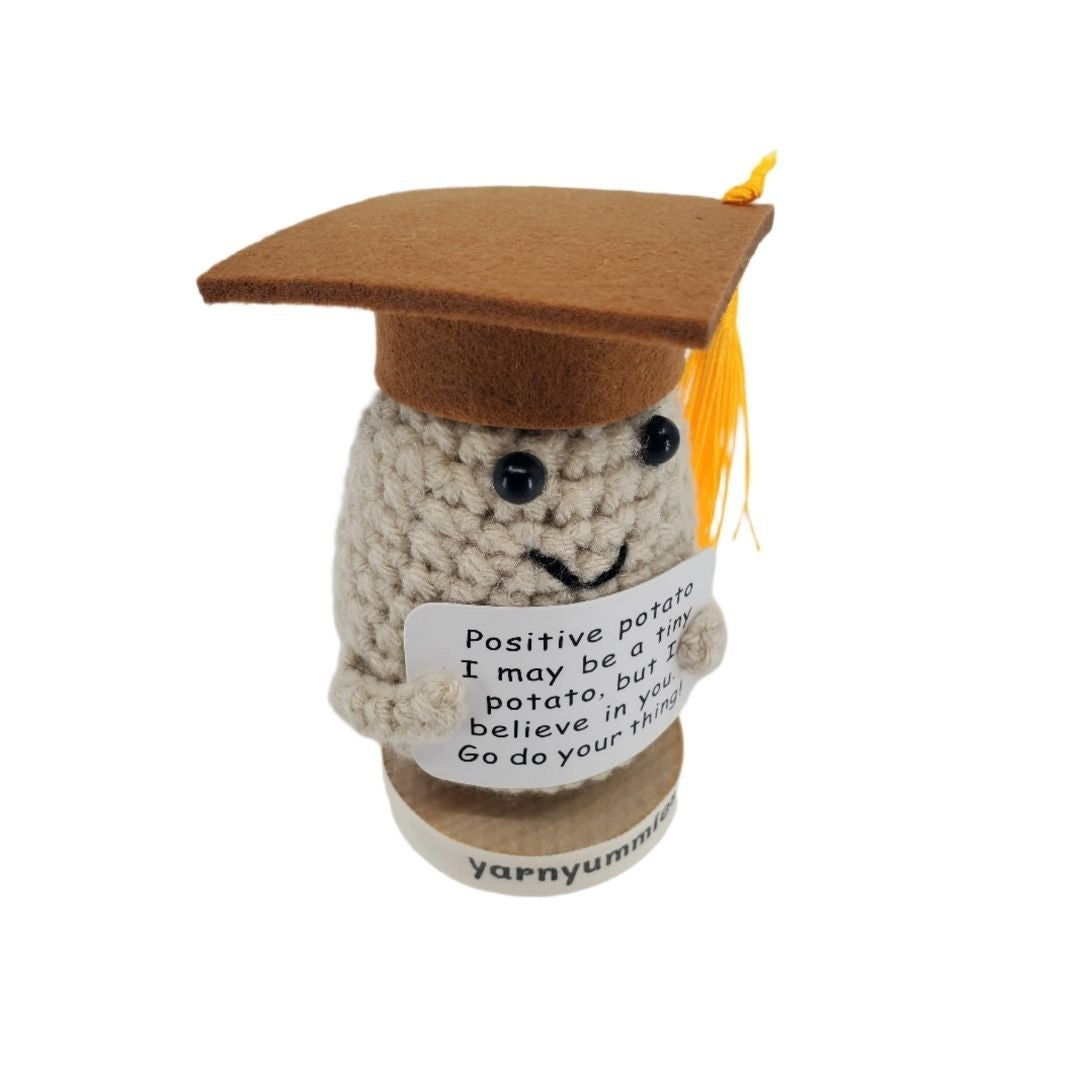 Crocheted positive potato character with a graduation cap and message on a white background