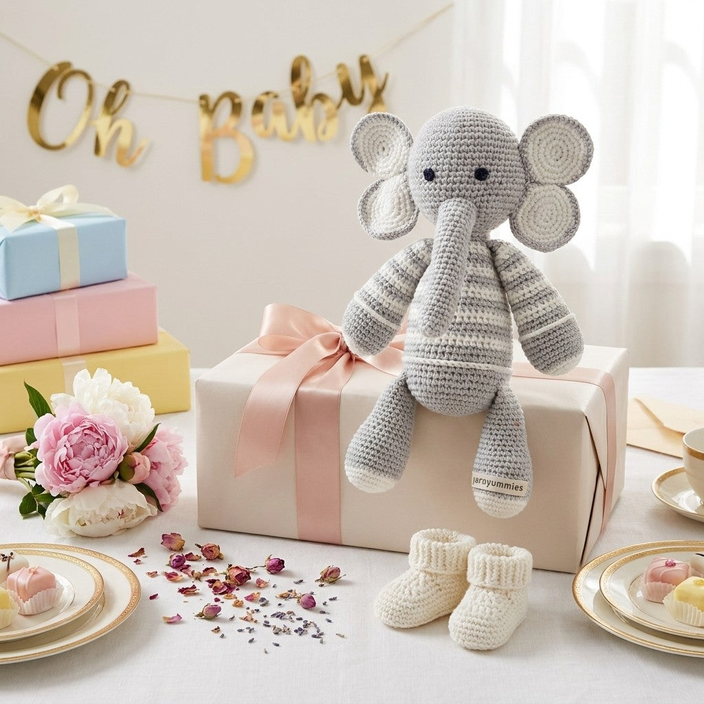 Crocheted elephant toy on a gift box with 'Oh Baby' banner and baby shower decorations.