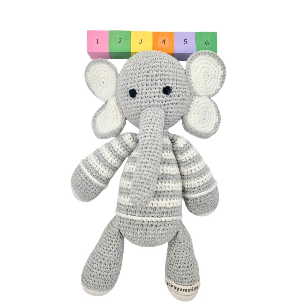 Crocheted elephant toy with a height measurement chart on a white background