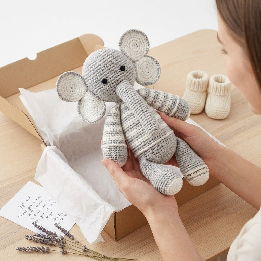 Person holding a crocheted elephant toy with baby booties in the background