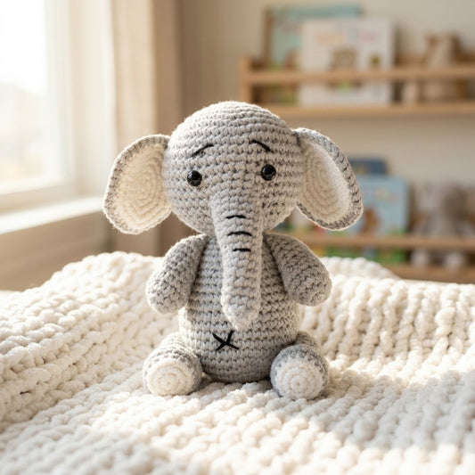 Crocheted elephant toy on a soft surface with a blurred background