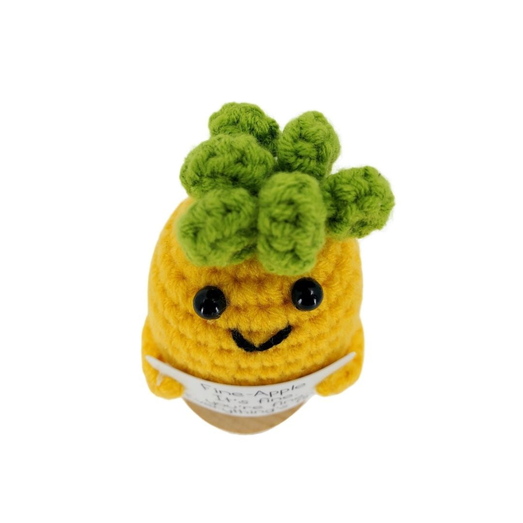Crocheted pineapple with a face on a white background