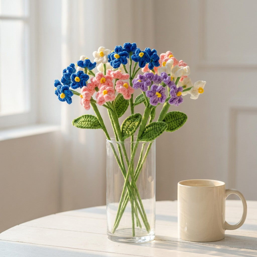 Vase with colorful knitted flowers on a table next to a mug.
