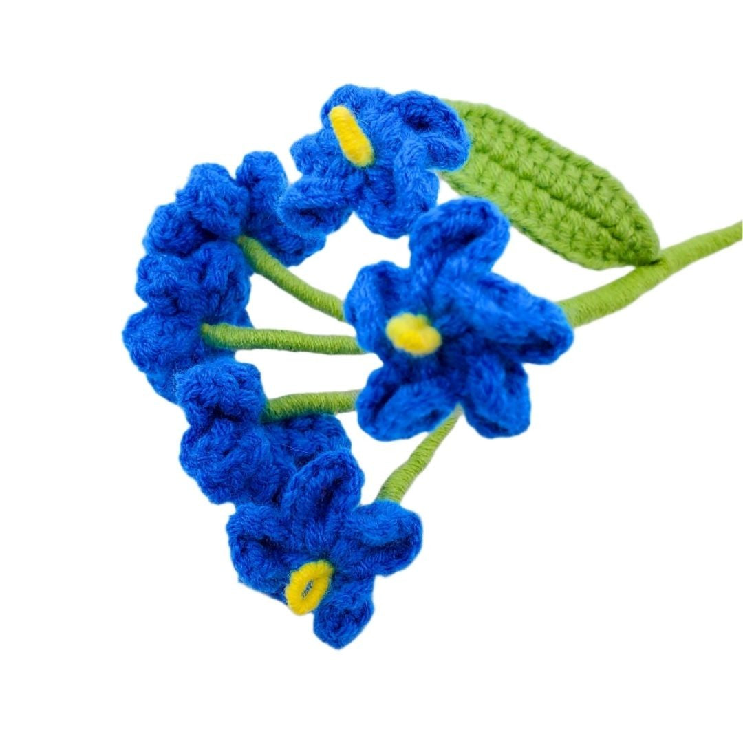 Crocheted blue flowers with green stems and leaves on a white background