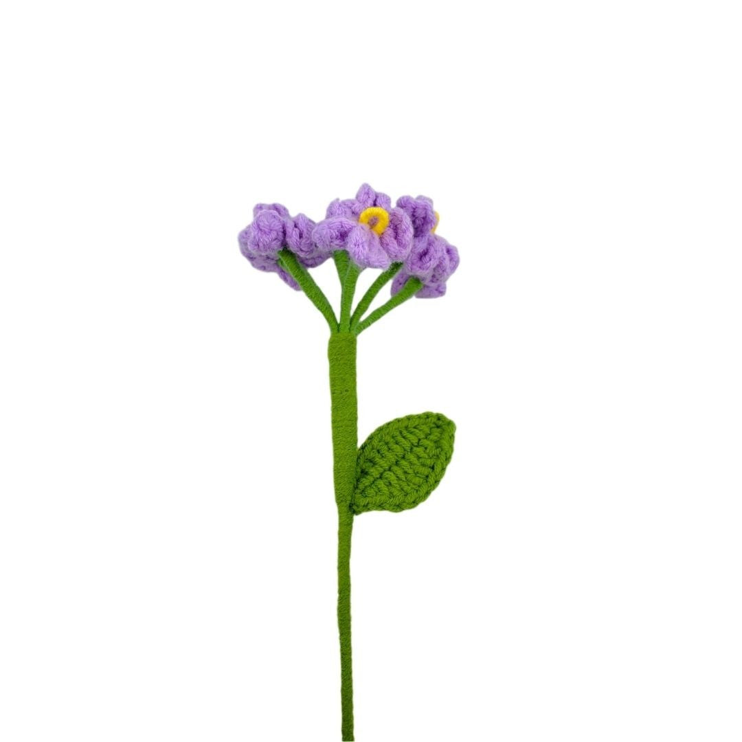 Crocheted purple flower with green stem on a white background