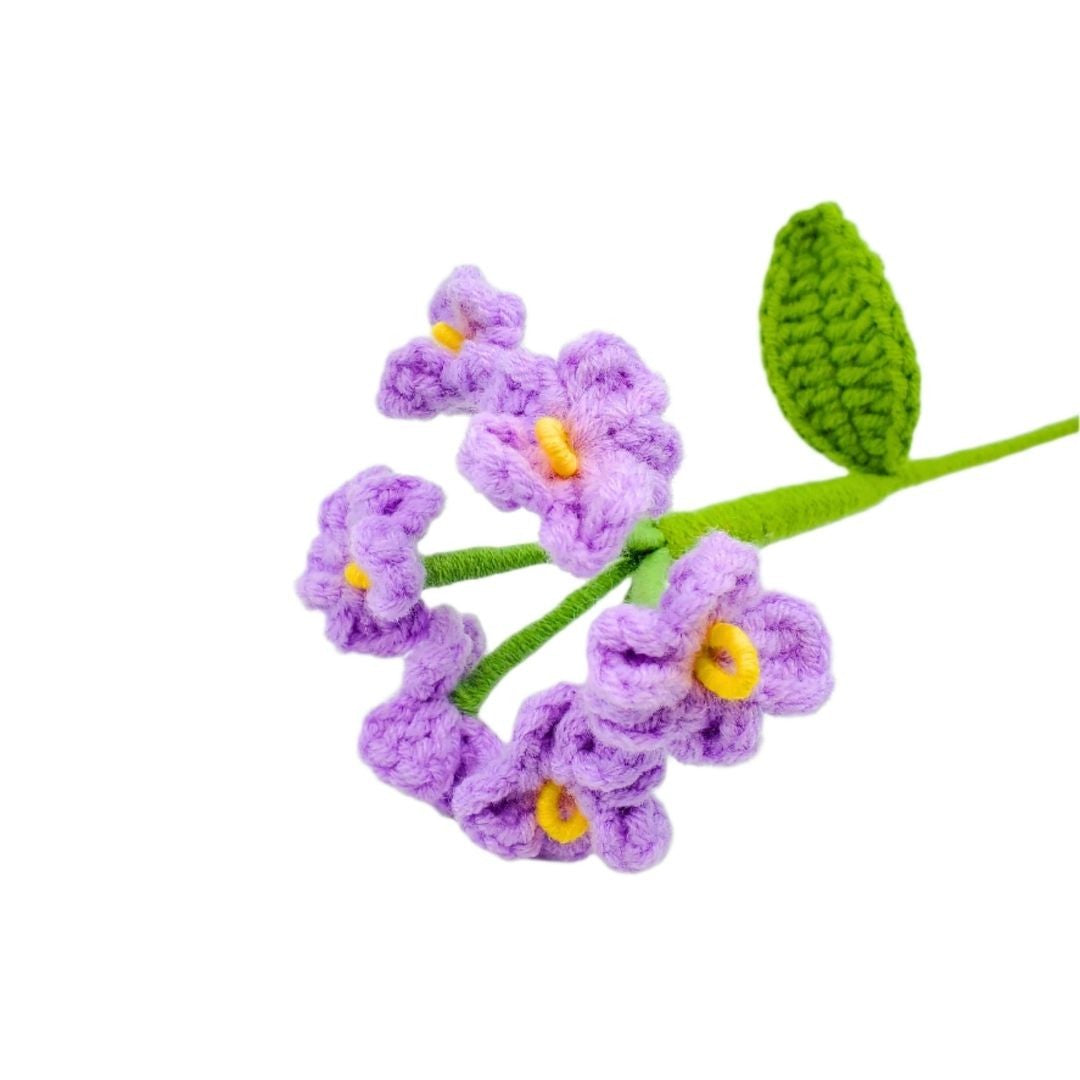 Crocheted purple flowers with green leaves on a white background