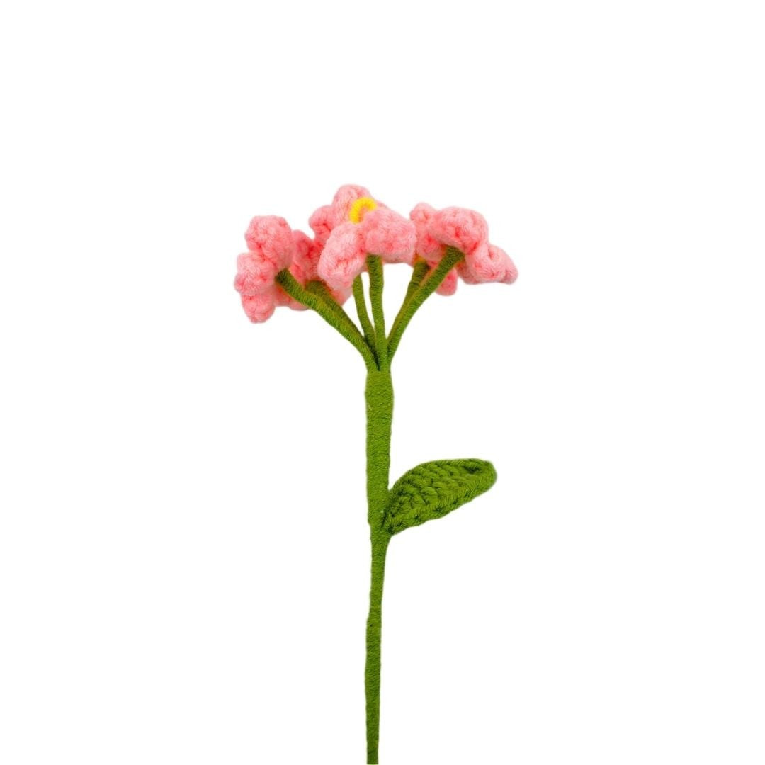 Crocheted pink flower with green stem on a white background