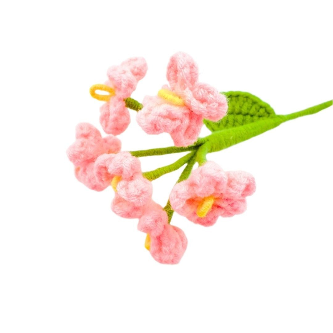 Crocheted pink flowers with green leaves on a white background