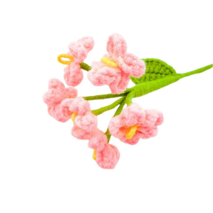 Crocheted pink flowers with green leaves on a white background