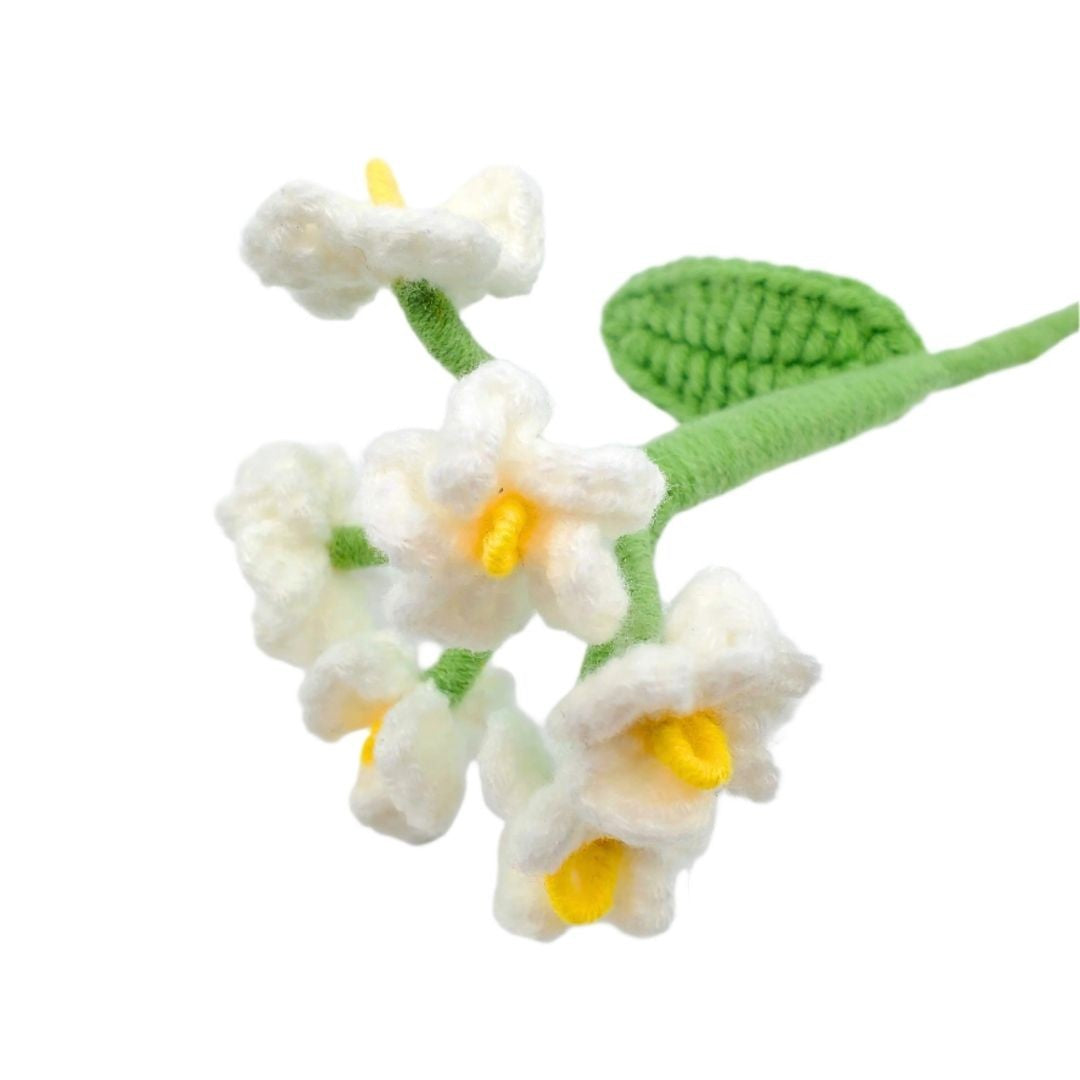 Crocheted white flowers with yellow centers and green leaves on a white background
