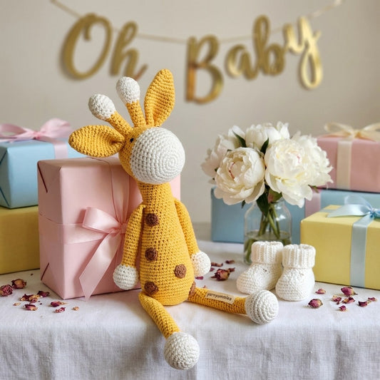 Crocheted giraffe toy with baby shower decorations including 'Oh Baby' banner, gifts, and flowers.