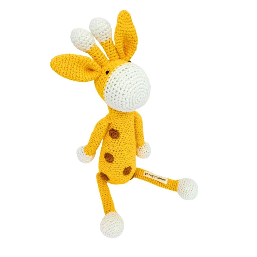 Crocheted giraffe toy with brown spots on a white background