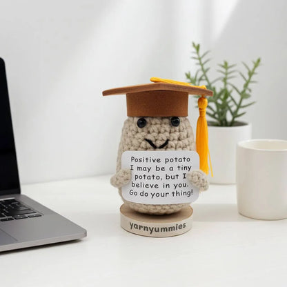 Decorative item resembling a small potato with a graduation cap and laptop on a desk