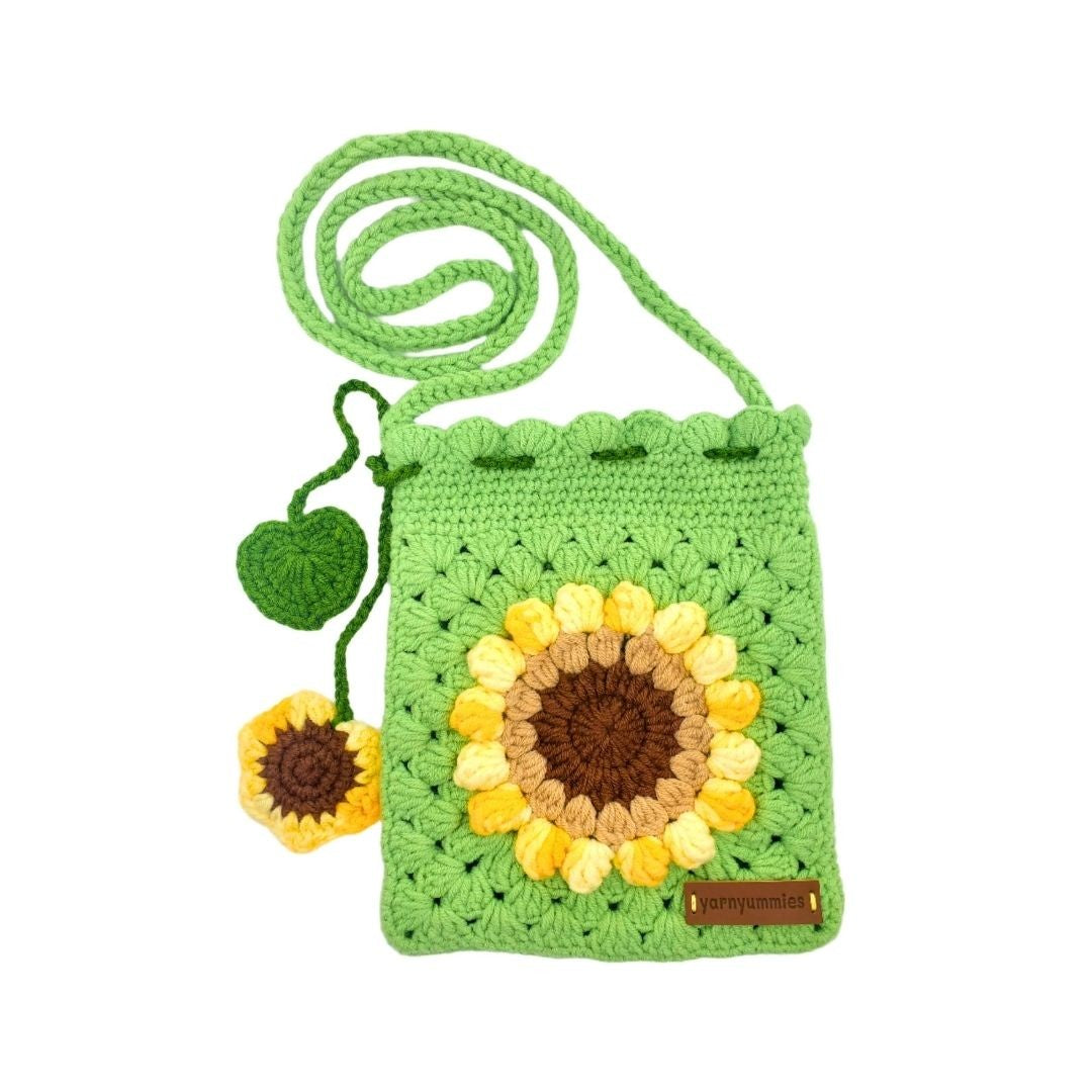 Green crochet bag with sunflower design and strap on a white background