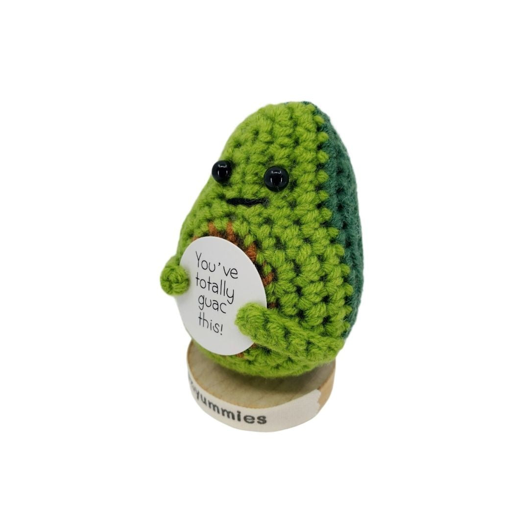 Crocheted avocado plush decor with a message tag on a white background