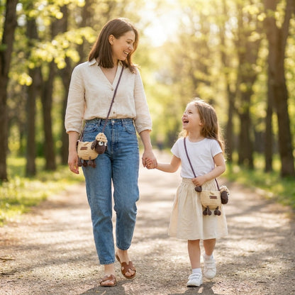 Woman and child walking hand-in-hand on a path in a park wearing the same crocheted crossbody sheep designed bag.