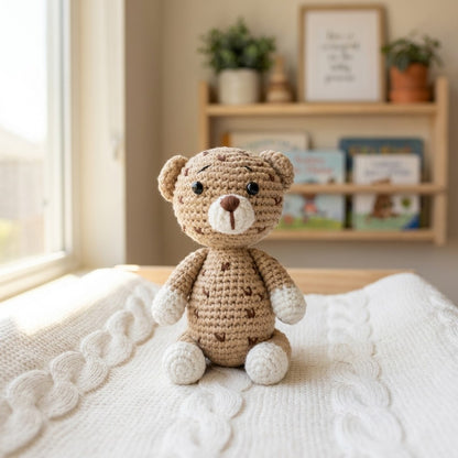 Crocheted leopard on a textured surface with a blurred bookshelf in the background