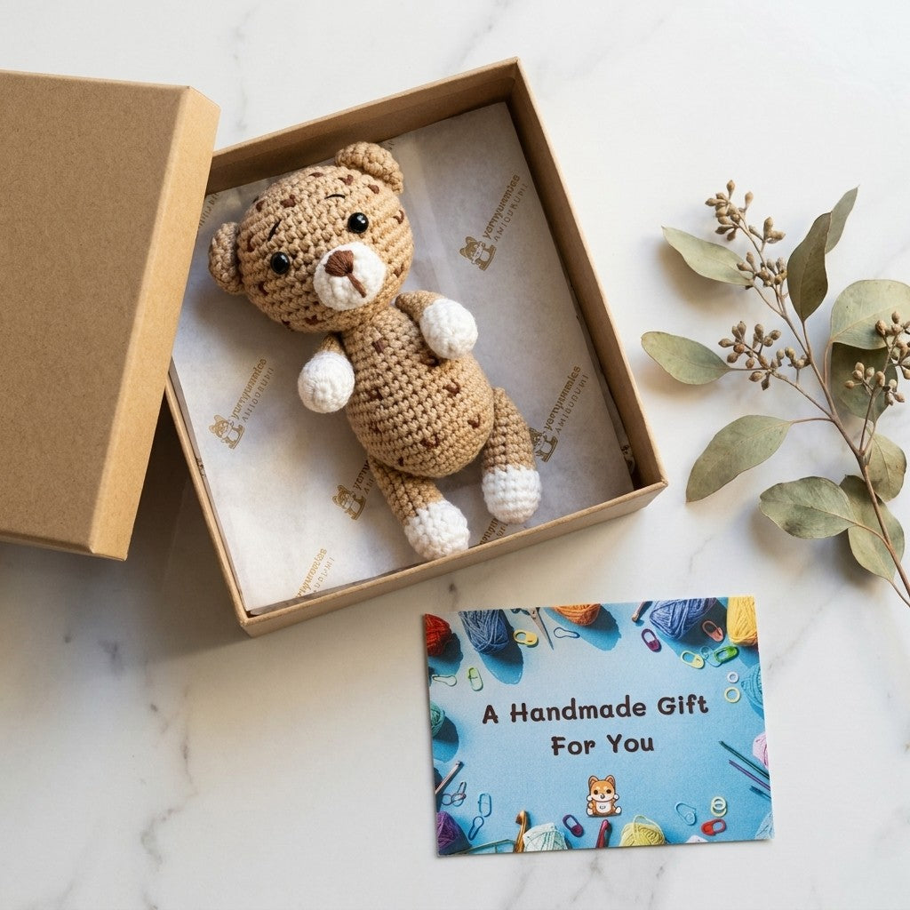 Handmade crochet leopard in a box with a 'Handmade Gift For You' card on a marble surface.
