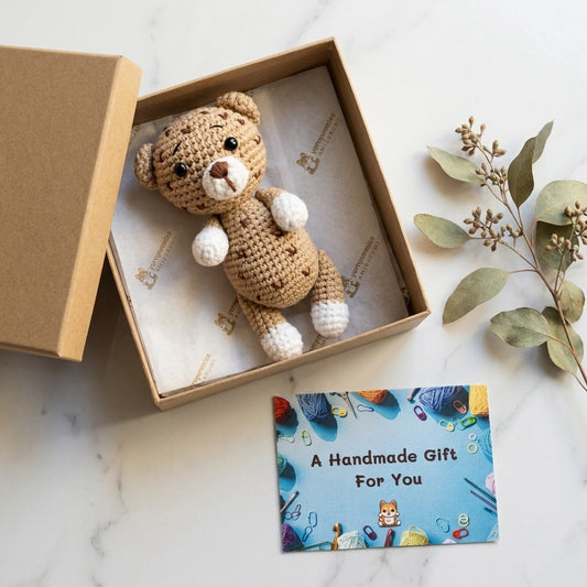 Handmade crochet leopard in a box with a 'Handmade Gift For You' card on a marble surface.