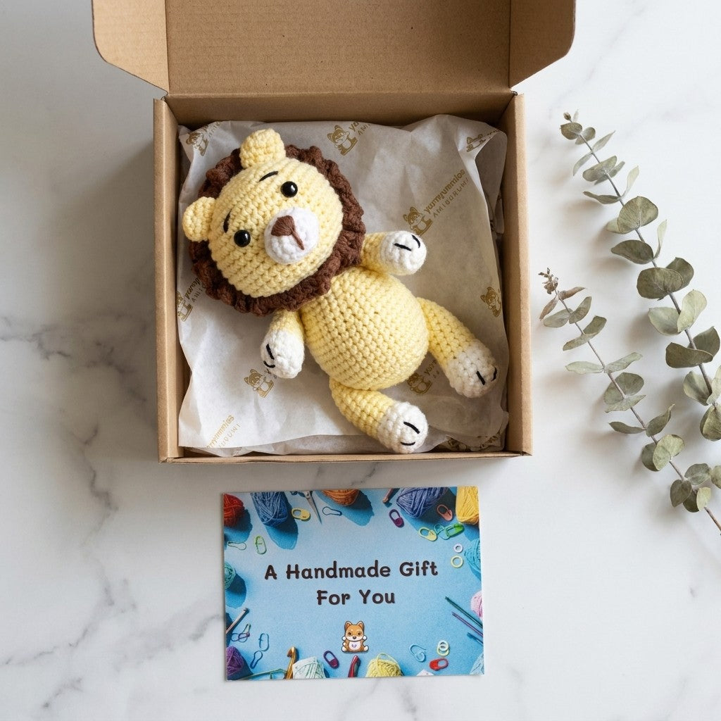 Crocheted lion toy in a box with a 'Handmade Gift' card on a marble surface.