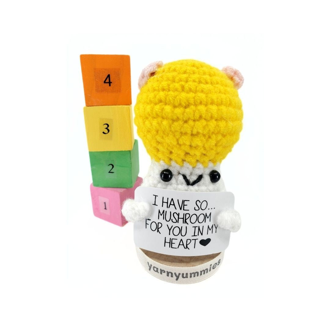 Crocheted mushroom character plus with colorful blocks and a heart message on a white background
