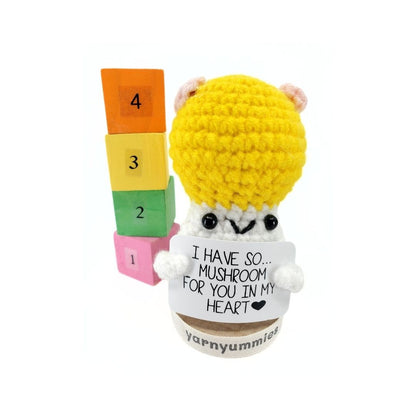 Crocheted mushroom character plus with colorful blocks and a heart message on a white background