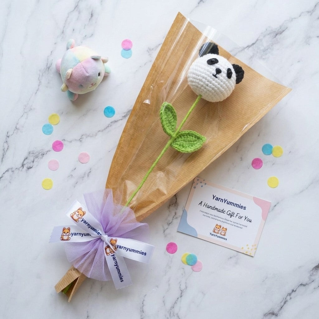 Handmade panda plush on stem wrapped as a bouquet and placed on a marble surface, featuring YamYummies branding.