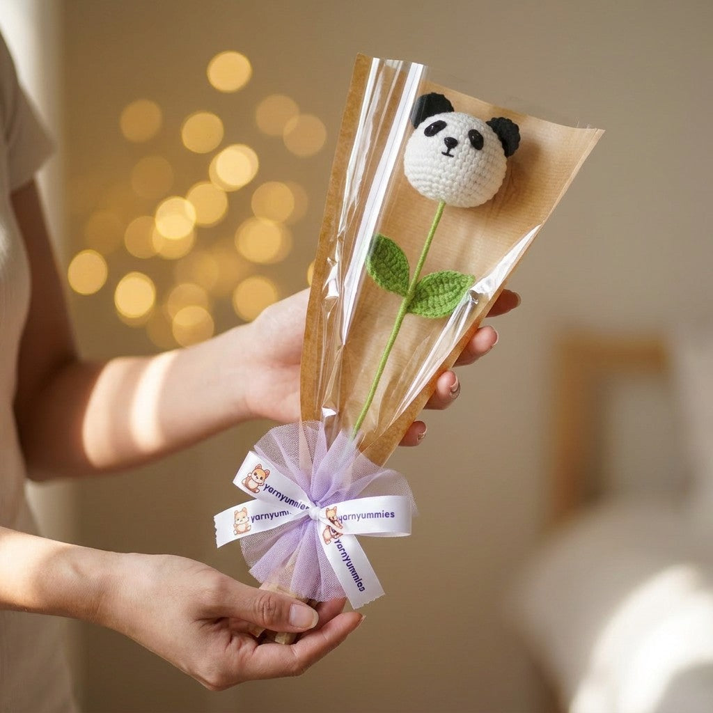 Bouquet of crocheted panda-shaped top held by a person against a blurred background