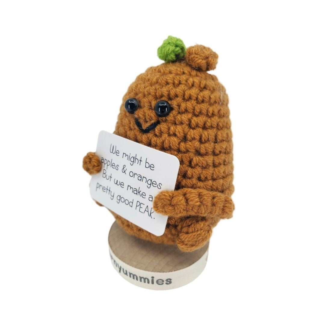Crocheted pear character holding a sign with text on a white background