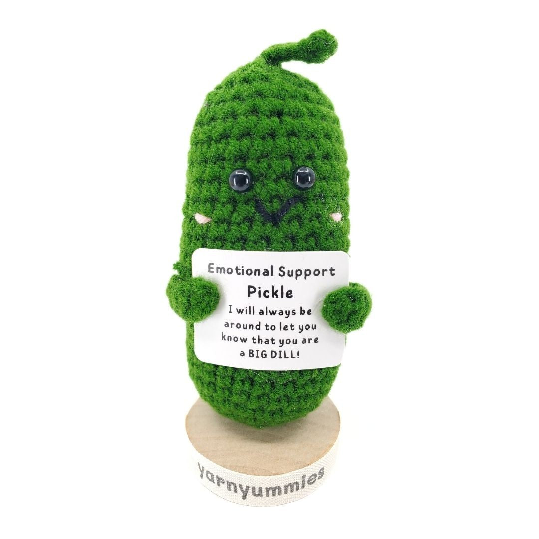 Green crocheted pickle plush with a label on a white background