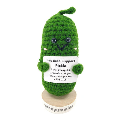 Green crocheted pickle plush with a label on a white background