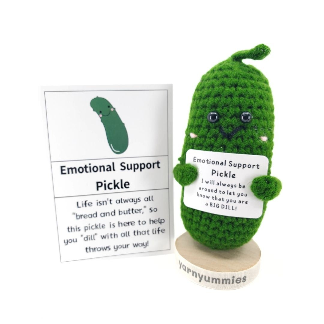 Crocheted pickle plush with a card and stand on a white background