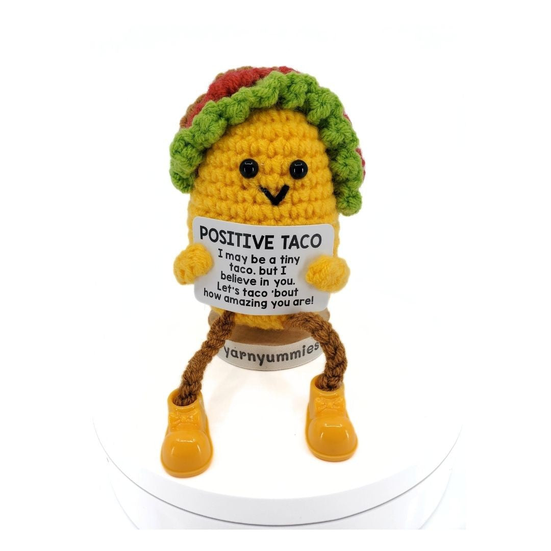 Crocheted taco plush toy with a sign and boots on a white background