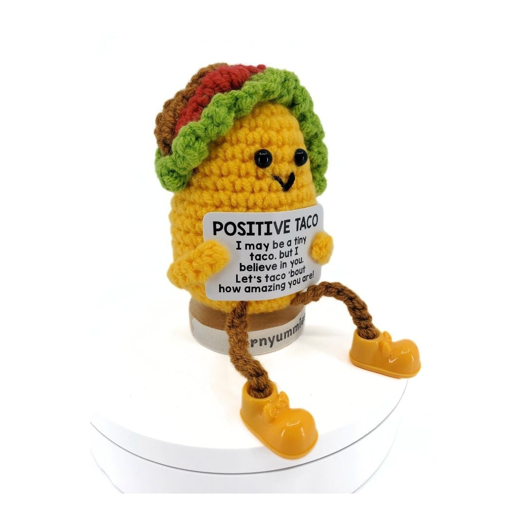 Crocheted taco character with a sign saying 'Positive Taco' on a white background