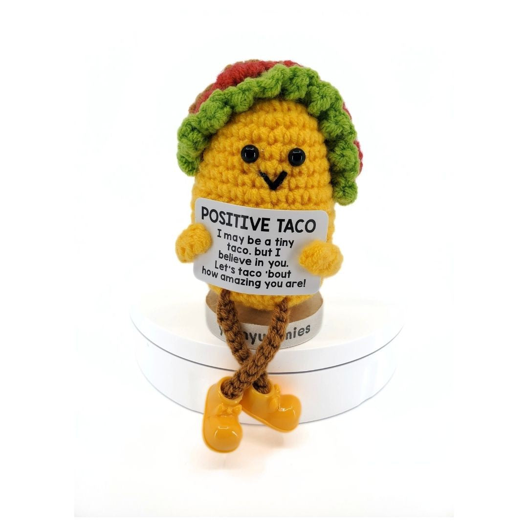 Crocheted taco plush toy with a sign and legs on a white background