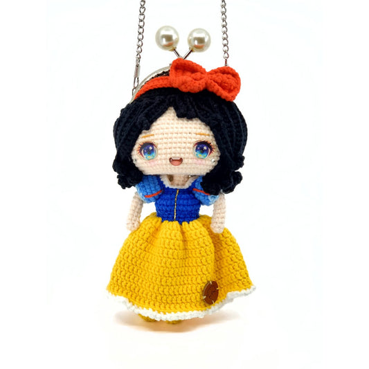 Crocheted doll inspired by Snow White with a yellow dress and blue jacket on a white background