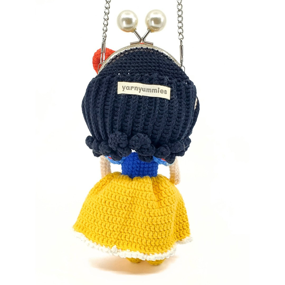 Crocheted character purse with black hair and yellow dress on a white background