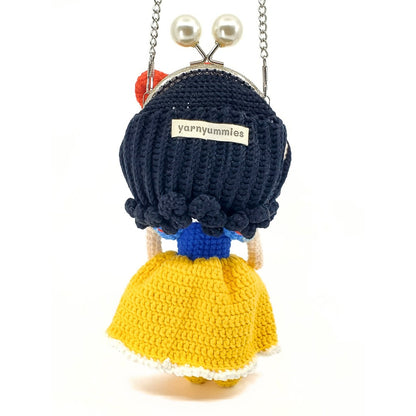 Crocheted character purse with black hair and yellow dress on a white background