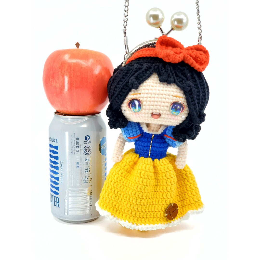 Crocheted Snow White inspired purse with an apple and a can on a white background