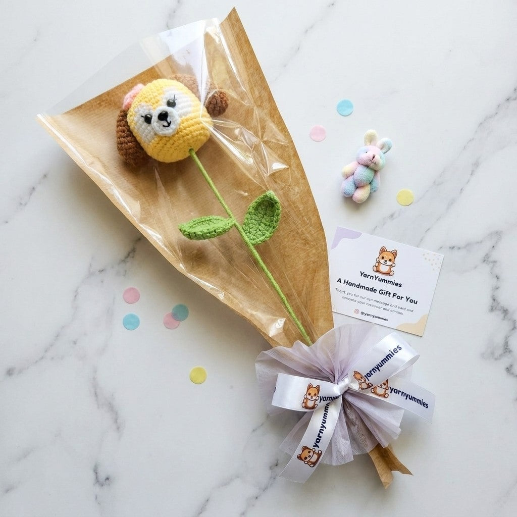 Handmade dog shaped flower with a bow on a marble surface, featuring the brand 'Yarn Yummies'.