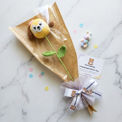 Handmade dog shaped flower with a bow on a marble surface, featuring the brand 'Yarn Yummies'.