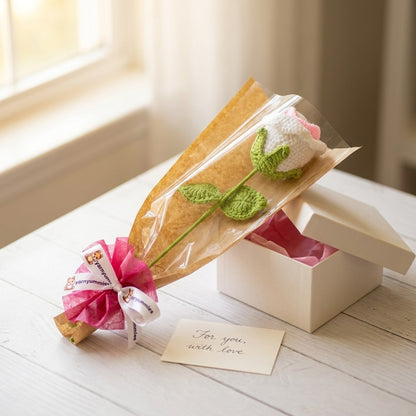 Gift with a crocheted flower and a small card on a wooden surface