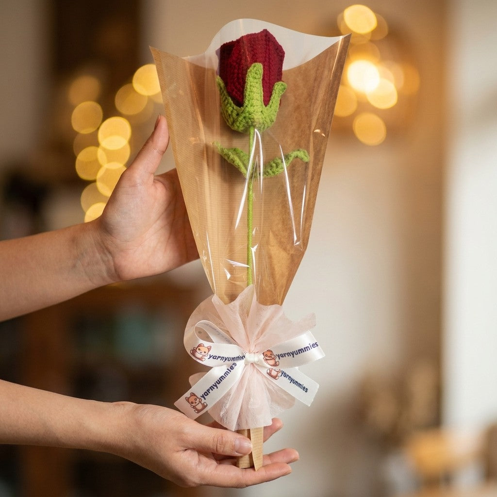 Hand holding a small bouquet of knitted roses with a blurred background