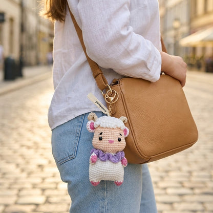 Person holding a brown leather bag with a sheep-shaped keychain on a blurred street background