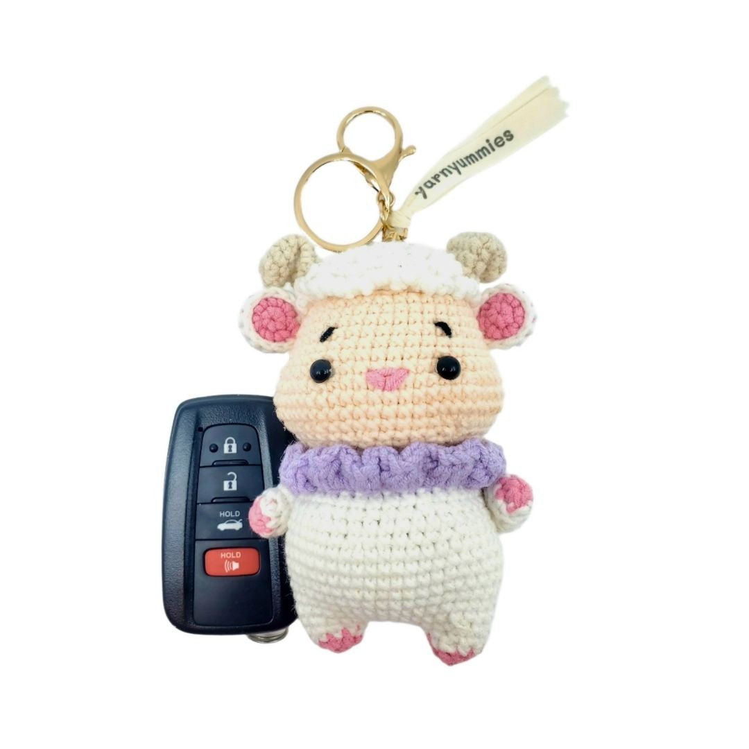 Amigurumi sheep keychain with a purple scarf on a white background