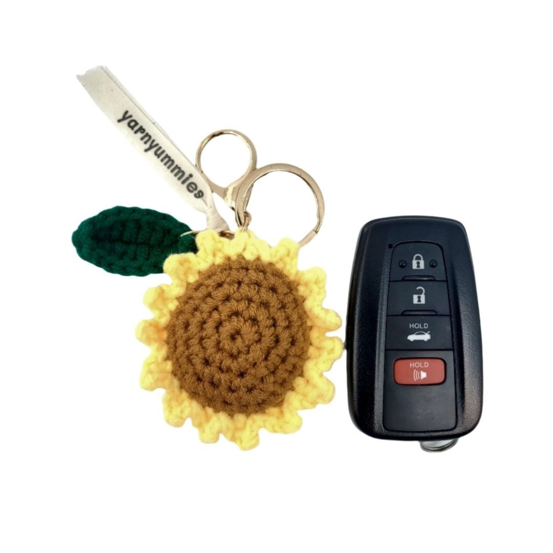 Sunflower-shaped keychain with a car key and remote control on a white background