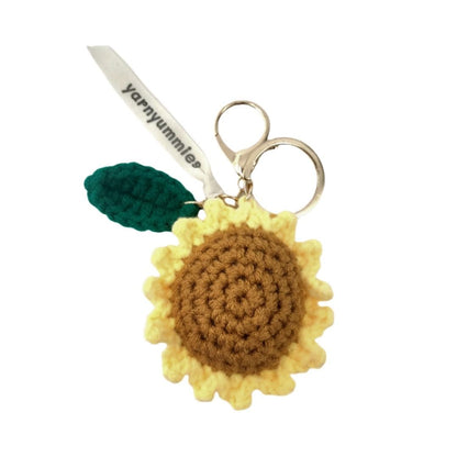 Crocheted sunflower keychain with a leaf and scissors on a white background